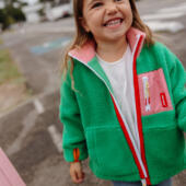 Kind draagt groene Green Candy Hello Hossy teddyjas met roze en fleece