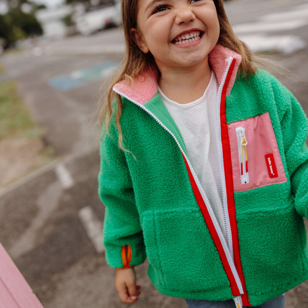 Kind draagt groene Green Candy Hello Hossy teddyjas met roze en fleece